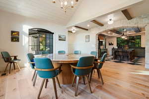 Dining space featuring a chandelier, light wood-type flooring, arched walkways, wainscoting, and recessed lighting