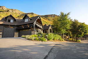 View of front of property with stone siding, driveway, board and batten siding, a mountain view, and a garage