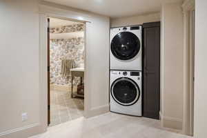 Laundry room with stacked washer / drying machine and light tile patterned floors