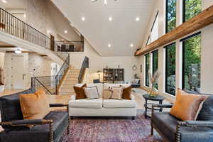 Living area with high vaulted ceiling, recessed lighting, wood finished floors, and stairway