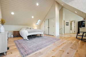 Bedroom featuring a skylight, recessed lighting, a closet, light wood finished floors, and high vaulted ceiling
