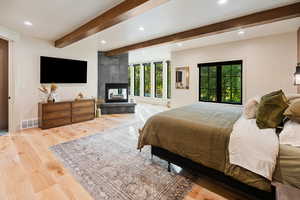 Bedroom featuring beam ceiling, light wood finished floors, a fireplace, and recessed lighting