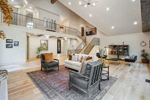 Living area featuring light wood finished floors, beamed ceiling, stairs, recessed lighting, and high vaulted ceiling