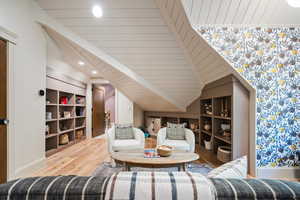 Sitting room featuring built in features, lofted ceiling, wood finished floors, and recessed lighting