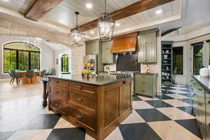 Kitchen featuring plenty of natural light, green cabinets, beam ceiling, custom exhaust hood, and a kitchen island