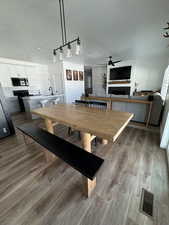 Dining room featuring a fireplace, light wood-style flooring, a textured ceiling, and ceiling fan