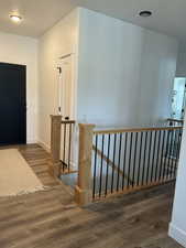 Hallway featuring dark wood-style flooring and an upstairs landing