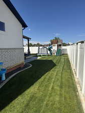 Fenced backyard with a playground, a trampoline, and a patio area