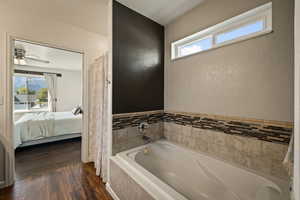 Bathroom featuring plenty of natural light, dark wood-style flooring, a garden tub, and ensuite bathroom