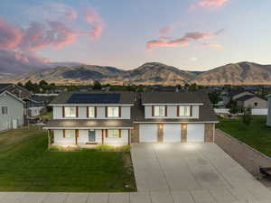View of front of property featuring a porch, solar panels, concrete driveway, and a mountain view