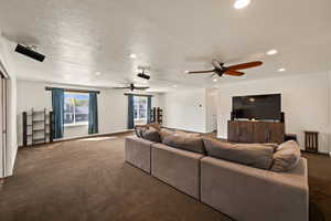Carpeted living area with recessed lighting and a textured ceiling