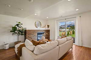 Living area with a textured ceiling, hardwood / wood-style floors, a stone fireplace, a mountain view, and recessed lighting