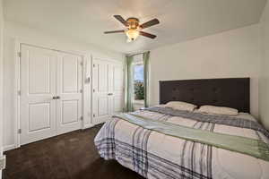 Bedroom featuring two closets, dark carpet, and ceiling fan