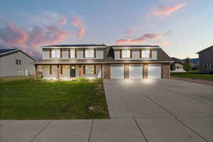 View of front of property with covered porch, concrete driveway, a front lawn, solar panels, and an attached garage