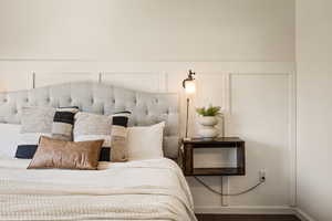 Bedroom with a decorative wall and wood finished floors