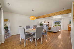 Dining space featuring beamed ceiling, light wood-style floors, and a fireplace