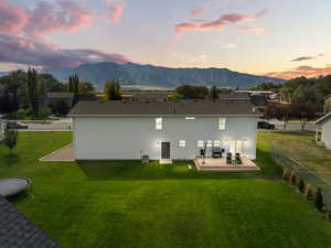 Back of house at dusk with a shingled roof and a deck with mountain view