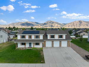 Traditional-style house with solar panels, covered porch, a mountain view, concrete driveway, and an attached garage