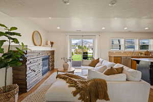 Living area featuring light wood-type flooring, a fireplace, a textured ceiling, and recessed lighting