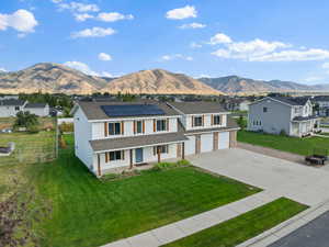 View of front facade with a porch, driveway, a mountain view, solar panels, and a residential view