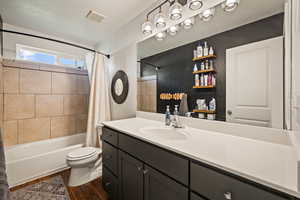 Full bath with shower / bath combo, dark wood-style flooring, and vanity