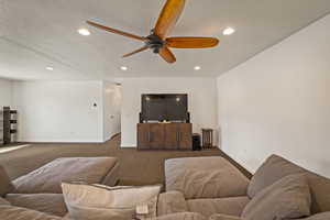Living area featuring carpet flooring, recessed lighting, ceiling fan, and a textured ceiling
