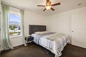 Bedroom with dark carpet, a ceiling fan, and a mountain view