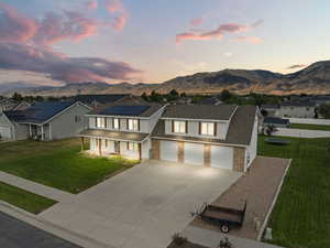 View of front of home featuring covered porch, concrete driveway, brick siding, roof mounted solar panels, and a mountain view