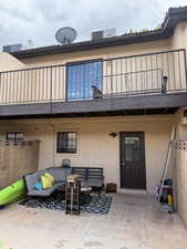 Back of property with an outdoor living space, stucco siding, a balcony, and a patio