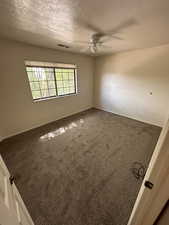 Carpeted spare room with a textured ceiling and ceiling fan