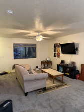 Carpeted living room with a textured ceiling and a ceiling fan