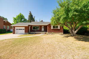 Ranch-style house featuring concrete driveway, a garage, a porch, brick siding, and a chimney