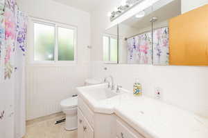 Full bathroom with vanity, light tile patterned floors, decorative backsplash, a wainscoted wall, and a shower with shower curtain