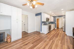 Kitchen with white cabinetry, light wood-style floors, a textured ceiling, appliances with stainless steel finishes, and backsplash