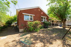 Back of house with brick siding, a trampoline, and a patio