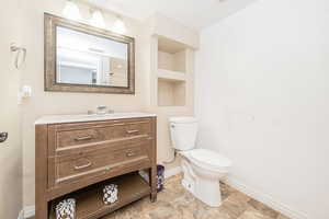 Half bathroom with vanity, built in shelves, and light stone finish floors