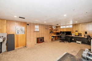 Home office with wood walls, light colored carpet, a textured ceiling, and recessed lighting