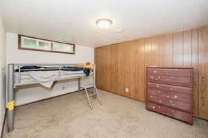 Bedroom with wood walls and light colored carpet