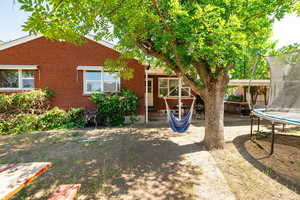Back of property with a trampoline, brick siding, entry steps, and cooling unit