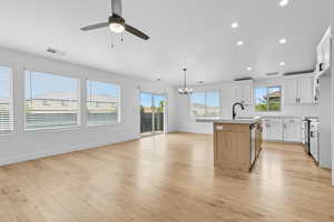 Kitchen featuring white cabinetry, a center island with sink, recessed lighting, stainless steel electric range oven, and light wood-style flooring