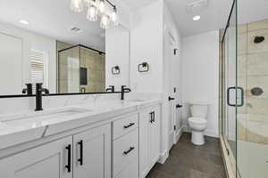 Full bathroom with a shower stall, double vanity, dark tile patterned flooring, and recessed lighting