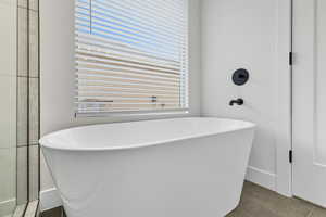 Full bath featuring a freestanding tub and dark tile patterned flooring