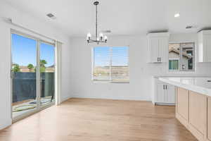 Unfurnished dining area featuring light wood finished floors, recessed lighting, and a chandelier