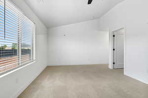 Spare room featuring lofted ceiling, light carpet, and ceiling fan