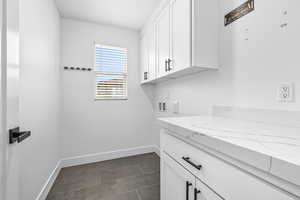 Laundry area with washer hookup, cabinet space, and dark tile patterned floors