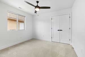 Unfurnished bedroom with light colored carpet, ceiling fan, and a closet