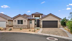 View of front facade featuring stone siding, stucco siding, decorative driveway, an attached garage, and a tile roof