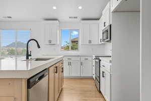 Kitchen featuring white cabinets, stainless steel appliances, recessed lighting, an island with sink, and light stone counters