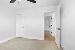 Unfurnished bedroom featuring light colored carpet and a ceiling fan