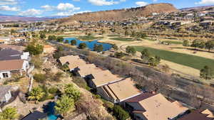 Aerial view of property and surrounding area with nearby suburban area, a water and mountain view, and a golf club